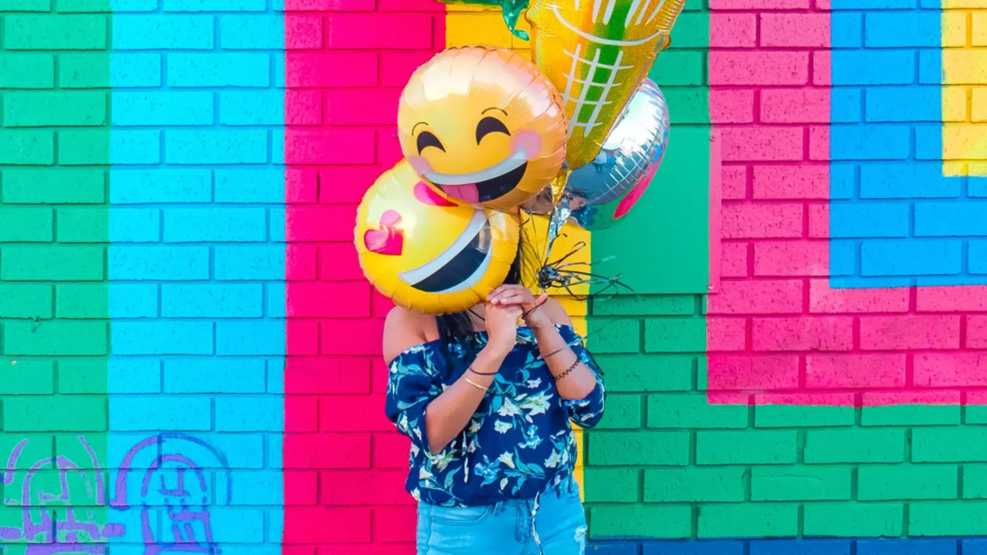 Ein Mädchen feiert ihren Geburtstag mit Luftballons vor einem bunten Wandgemälde.