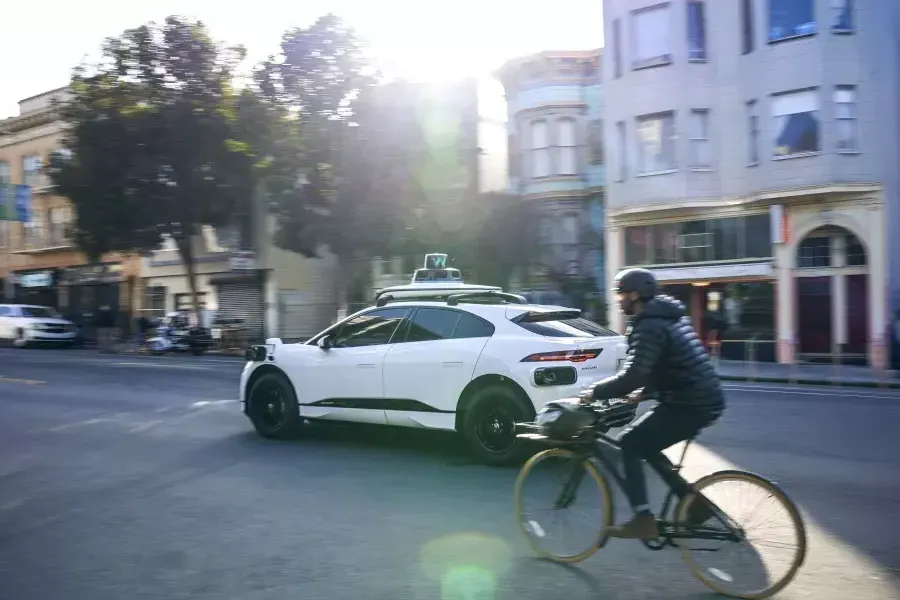 ウェイモの車の後ろで自転車に乗る人